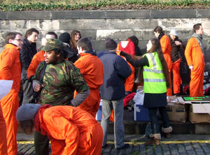 An organiser handing out orange boiler suits on Regent Terrace, whilst people get ready for the demo.