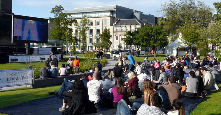 Groups of people waving, standing on the steps of the Omni Centre, with the St James Centre in the background