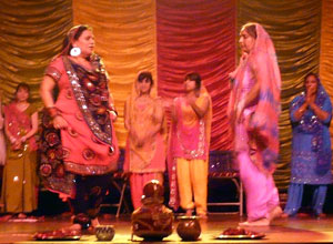 Two mature women dance facing each other, as younger women watch on