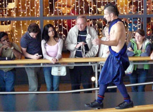 People watch as an acrobat trickster figure walks along the banister