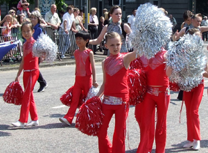 Children in red costumes with silver pompoms