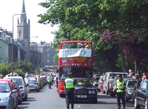 Black limousine surrounded by Lothians & Borders police, in front of the red open topped bus
