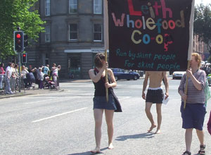 Three marchers with the Leith Wholefood Coop Banner