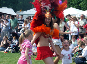 Woman in red and orange samba costume dancing with two little girls