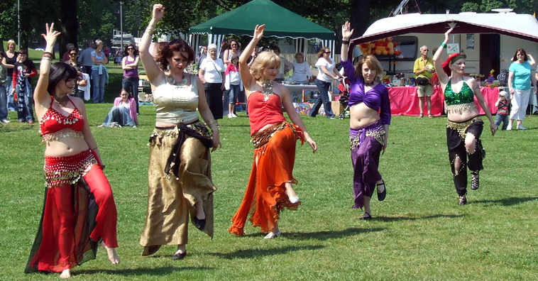 Five women belly dancing in line with left legs hitched