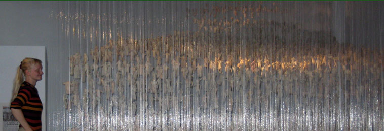 Sound engineer Kate stands on a chair to look across the middle rows of figures, which can be seen glowing through the shimmering nylon wires