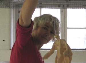 Jane holding a larger figure on its wire and looking at it with a contemplative expression