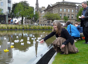 Fay Young stoops to cast a lotus on the pond as Gordon Munro stands by