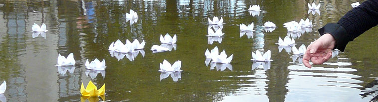 White paper lotus blossoms float on water as a hand can be seen casting a lotus out