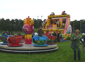Roundabout with giant teacups in front of 20 foot high inflatable children's slide with huge Fred Flintstone and Barney Rubble figures