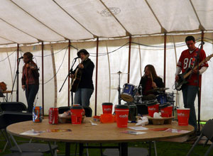 Four piece band - female violinist, female acoustic guitarist (in hat) male drummer and male bassist