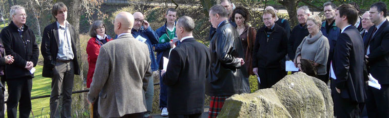 Relative Colin Cargill shares his thoughts as people listen in reflection, with the monument in the foreground