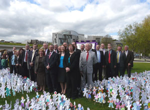 MSPs stand as a group with the Parliament in the background