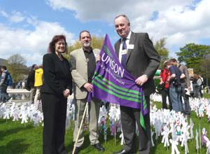 Sarah, Ewan and Dave gathered round a purple UNISON flag with three green stripes