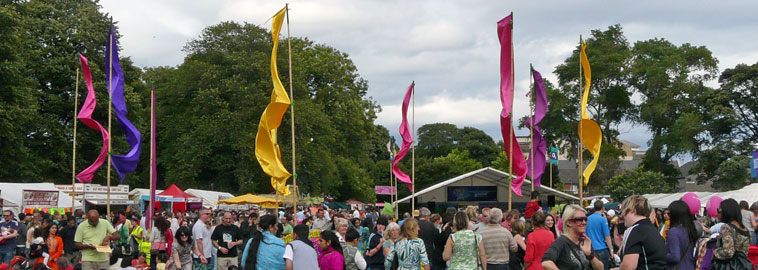 View of crowd around the Garden Stage with the many coloured pendant flags blowing in the breeze