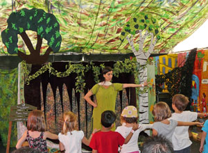 Storyteller in olive green engaging children in dance moves