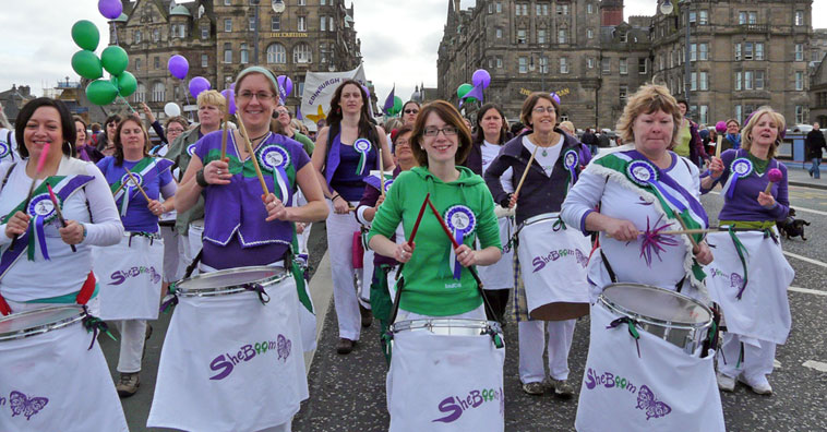Sheboom, marching down North Bridge, drumming with lilac and green tops and white trews