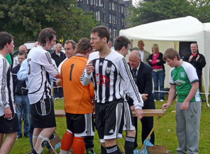 Players in the black and white stip of Leith Athletic going round the  medals table