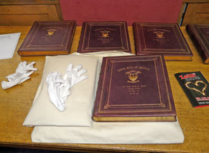 Five volumes bound in burgundy coloured leather with gold leaf and white cotton gloves