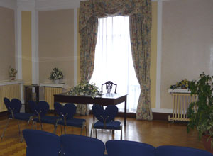 Polished wooden table with flowers in front of a green and yellow curtained window
