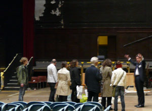 Tour party looking toward the stage as they listen to gesticulating guide