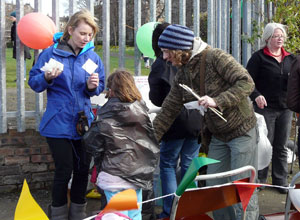 Women helping a child get ready to paint a brick - black bin bags in good supply