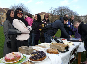 Women standing and laughing behind a table with cakes on