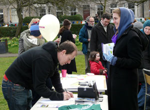 An entrant fills in his form as a smiling woman in a purple scarf watches on