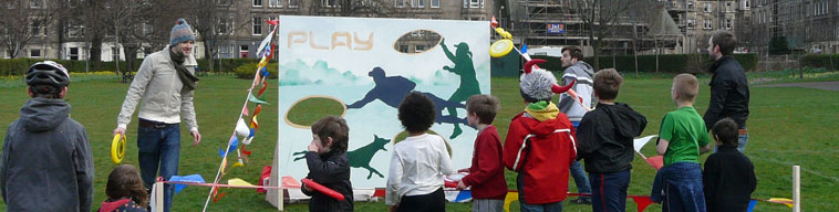 Children throwing frisbees at target board with Elgin Terrance and the scaffold surrounded Calton Centre in distanceCalton Cne