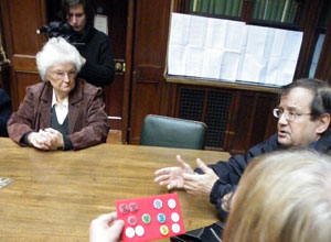 Two women and a man seated round a table discussing badges
