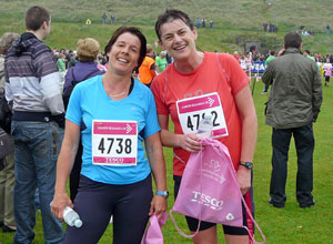 A rather tired  but cheerful woman in a blue tee shirt with a rather tired but cheerful woman in a red tee shirt
