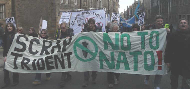 Marchers with banner "SCRAP TRIDENT (ban the bomb symbol) NO TO NATO!"