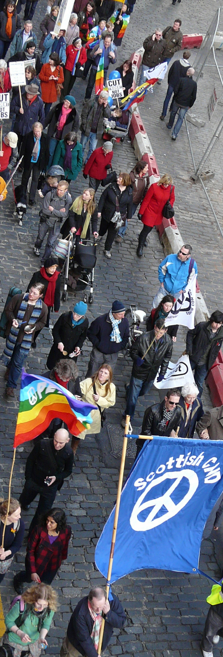 View of march from above, as it walks down Victoria St, a blue Scottish CND banner in the foreground