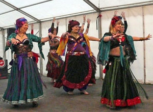 Six women dancing in tribal costumes with three in the foreground