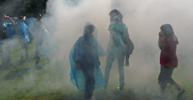 Spectators surrounded with dry ice as the backlighting makes their recyclable ponchos translucent