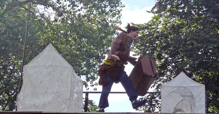 Woman with suitcase dancing for joy with trees in the background