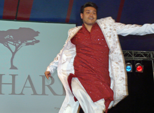 Man dancing in white suit with gold embroidery and long red shirt