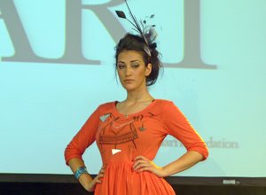 Woman posing in feathered head piece and orange dress