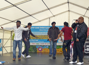 Four men dancing on stage as GTown Desi DJ raps on
