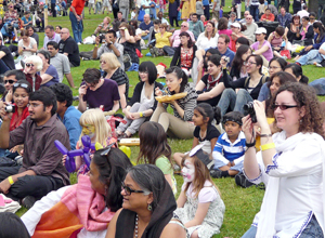 People seated applauding, watching and filming a performance