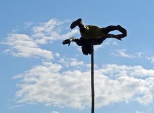 Young man spinning on top of a pole with clouds in the background