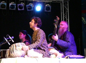 Three seated musicians under a purple spotlight