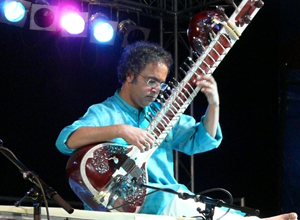 Man in turquoise shirt playing the sitar