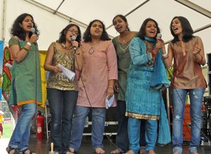 Six women stand singing as a choir
