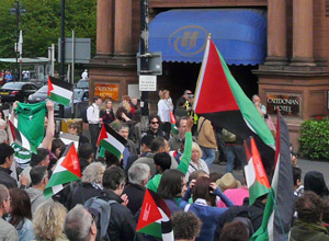 People waving Palestinian flags outside the entrance to the Caledonian Hotel