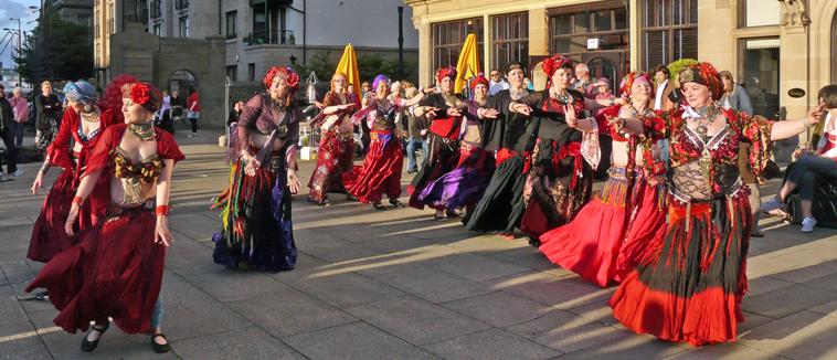 Twisted Tails belly dancers performing in red, black and purple costumes with turbans