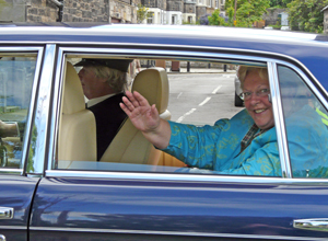 Margo Macdonald in tourquoise waving from the window of a black Daimler