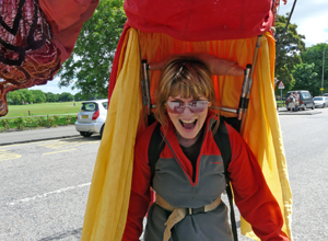 Woman looking into the camera from beneath a giant red and orange puppet