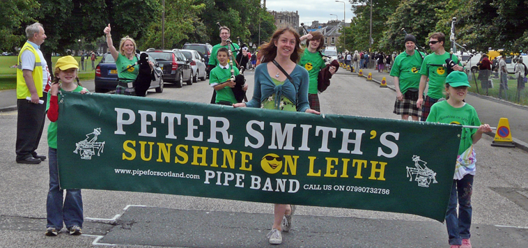 Woman (centre) with two girls holding bannner "PETER SMITH'S SUNSHINE ON LEITH PIPE BANC