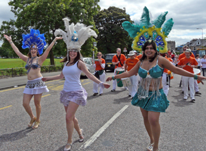 Three women dancing in blue and white costumes with blue and white feathered head dresses